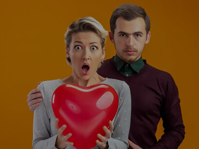 A romantic Valentine's Day moment unfolds as a young couple playfully cover their faces with a heart-shaped balloon, radiating love and happiness