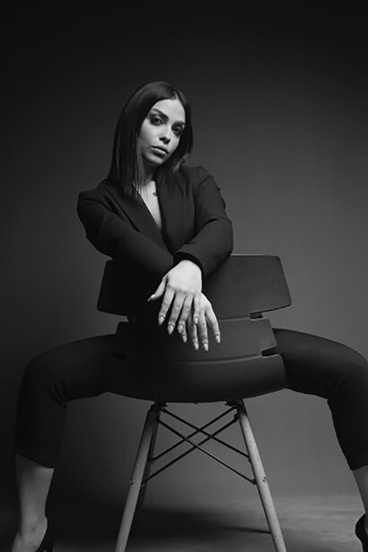 A woman seated in a chair, wearing a suit