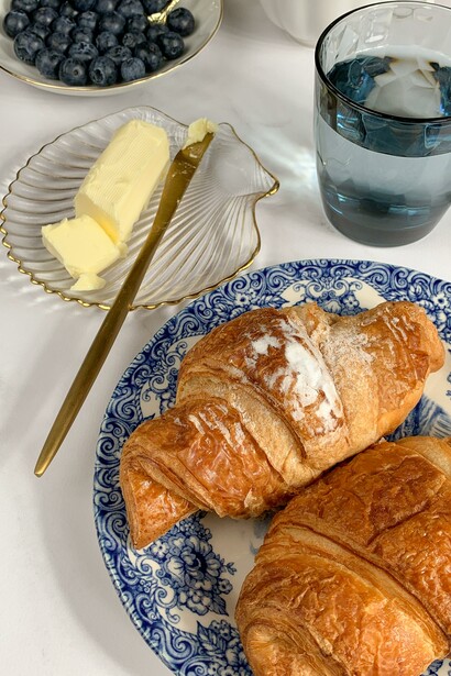 Two croissants next to some butter and blueberries