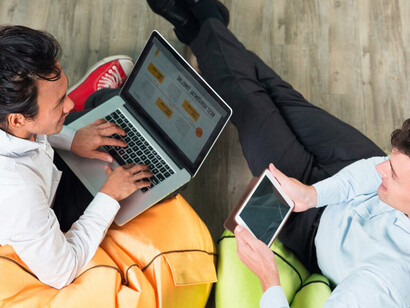Collaborating on a tablet and laptop, two businessmen strategize on networking platforms, group guidelines, global connectivity, and effective social media engagement