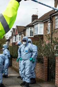 A policer officer holding up the police tape for the crime scene investigators
