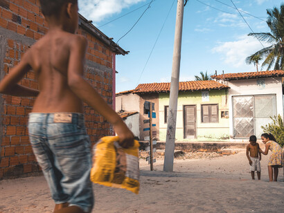 Criança corre com saco de salgadinhos em comunidade brasileira