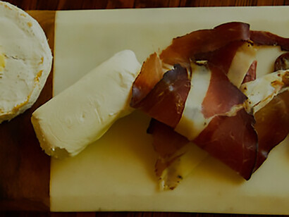 A tantalizing array of cured meats is skillfully arranged, complemented by the allure of a perfectly poured glass of wine