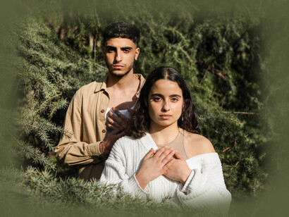 A couple with their hands on their hearts, in the forest