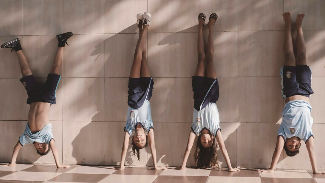 Four student-athletes leaning against the wall represent the balance they maintain between their academic and athletic responsibilities, demonstrating teamwork and resilience
