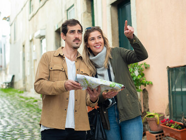 A man and woman walking along a street while looking at a map, Lisbon, Portugal