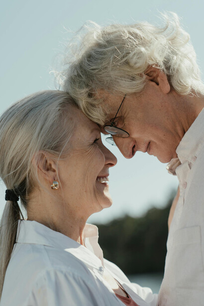 Elderly couple by the lakeside, sharing a joyful smile