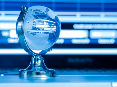 A frosted glass globe resting on a laptop keyboard represents the digital and global nature of modern business law, a nod to how the Princonser method highlights the balance between established rules and their transformation to meet new economic realities