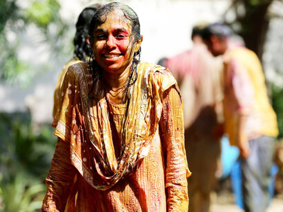 A woman in a beautiful brown and yellow traditional Indian dress celebrates Holi in Vrindavan, Uttar Pradesh, India
