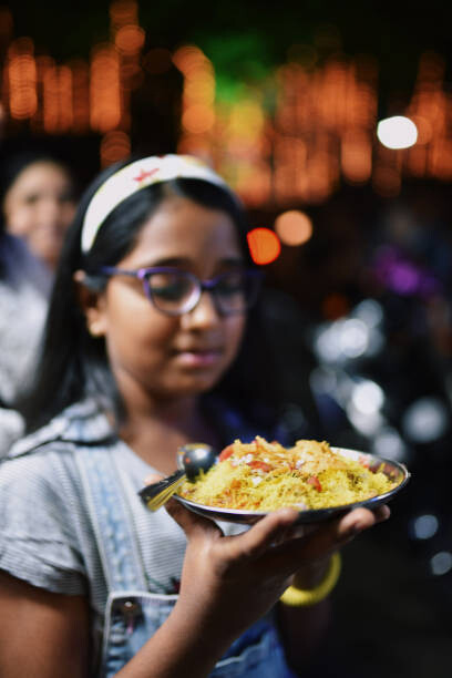 Family enjoying street food at night, with girls in Mumbai trying local delicacies