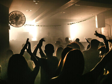 A crowd celebrates on a dance floor under club lighting, moving to electronic dance music