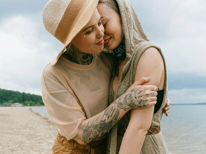 Two people sharing an embrace by the shore, representing the healing power of safe human connection