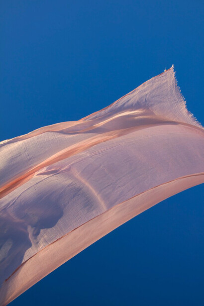 A person gracefully waves a fabric in the air, highlighting its eco-friendly and biodegradable nature