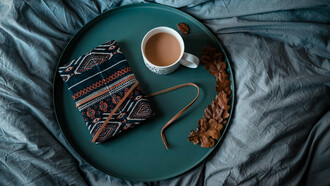 Una libreta de notas cerrada y vacía, junto a una tasa de café