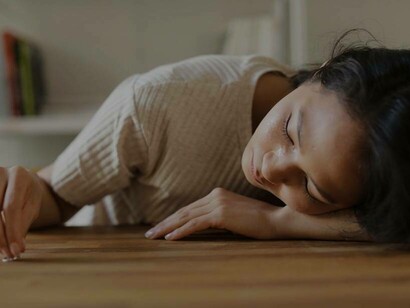 A woman playing with her wedding ring while resting her head on the table after the amount of crying she endured when she realized that her partner was a cheater