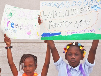 Two girls holding signs to end childhood poverty