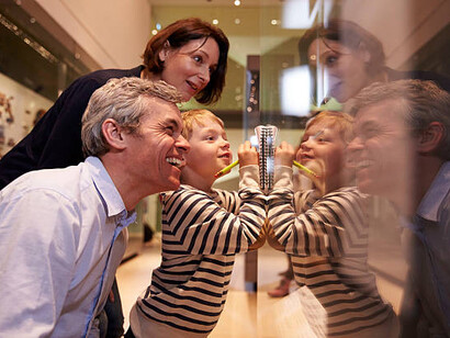 While exploring a museum, a family views artifacts in a glass case, experiencing the educational and emotional value of art together