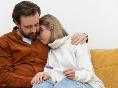 Couple sitting on the couch, anxiously examining a pregnancy test as they face the challenges of infertility