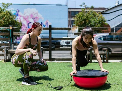 A trainer supervising a focused workout session on a stability platform, representing the holistic approach that complements minimally invasive treatments