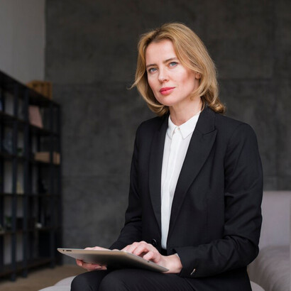 A thoughtful businesswoman sitting with a tablet, representing women in business, female entrepreneurship, and the connection between economic growth and gender equality