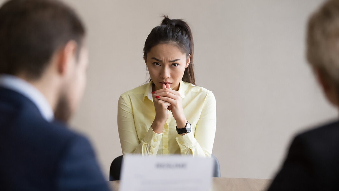 Young professional facing anxiety and pressure during a formal job interview in a modern office setting