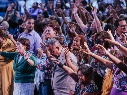 Hands raised high, this vibrant community comes together in a powerful expression of faith, seeking connection and solace in a world of uncertainty