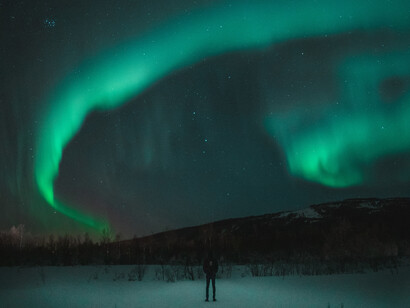 Indivíduo observa sozinho o fim de uma aurora boreal. Não é melhor deixar o universo fluir, alheio a nós e a nossas vontades?