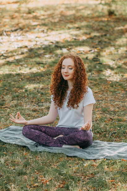 Healthy woman doing yoga outdoors on the grass in a park