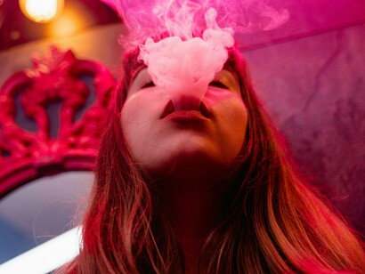 A woman vaping in front of a store, showing how popular and socially acceptable vaping has become in public spaces