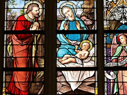 Una vetrata che raffigura la Natività, la scena biblica della nascita di Gesù Cristo. Iconografia cristologica in vetro policromo: funzione didattica e contemplativa dell’arte sacra