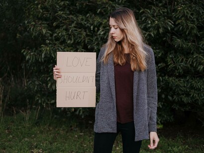 A woman holding a cardboard sign and dealing with the recent loss of a lover