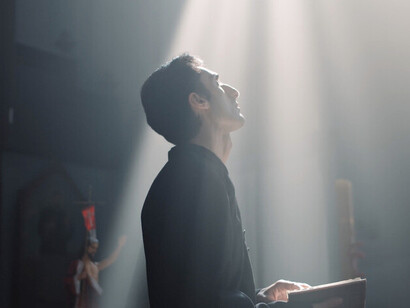 With the Bible held close, the priest embodies the weight of history and belief, reminding us of the delicate balance between reverence and manipulation