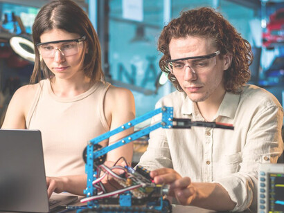 Pair of individuals in VR goggles conducting robotics experiments amidst lab equipment and robots