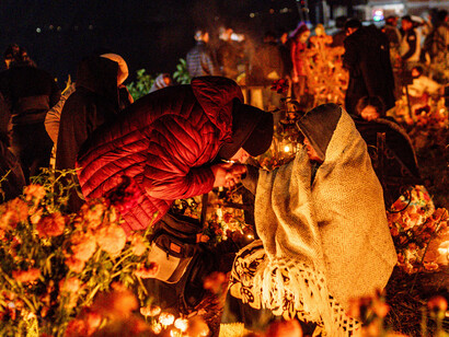Families gather in a cemetery illuminated by candles during Mexico’s Day of the Dead, paying tribute to departed loved ones