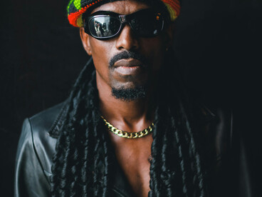 Portrait of a man wearing sunglasses and a hat, inspired by classic reggae aesthetics