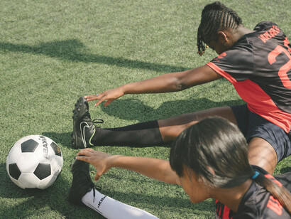 Dos jugadoras de fútbol femenino elongando