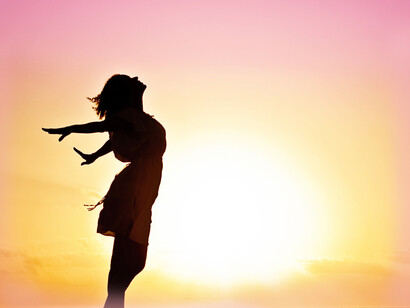 A woman with her arms stretched out in the sunshine
