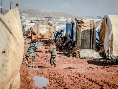 Two children walking on the road of a Syrian refugee camp during the war in Syria