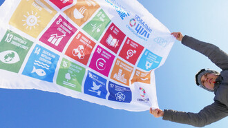 A woman holds a flag of the SDG of the UN