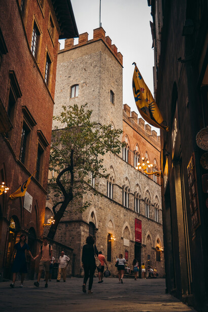 A crowd of people strolling down a charming street lined with historic buildings in Siena, Italy