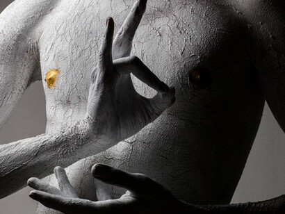 An individual transforms through art, their body dusted in white powder like a symbol of rebirth