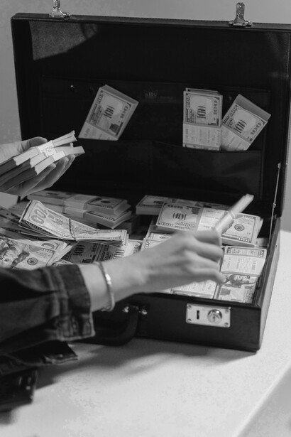 Mulher manuseando notas dentro de uma mala preta. A cena ilustra simbolicamente as suspeitas de irregularidades financeiras frequentemente associadas às crises políticas