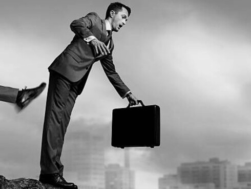 A man being pushed off a cliff from behind, symbolizing manipulation in business life