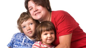 Una madre abraza a sus dos hijos