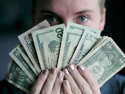 In a visual depiction of prosperity, a person holds a fan of U.S. dollar banknotes, capturing the essence of financial wealth and abundance