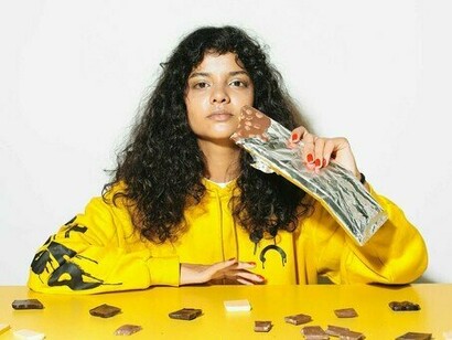 Mulher come chocolate. A voz aguda mal é notada. Mulher de cabelo chanel, sentada duas mesas adiante, mal levanta os olhos do teclado prateado do MacBook. Os dedos se movem com rapidez, talvez redigindo uma reclamação. Algo sobre um vestido que chegou no tamanho errado ou uma devolução atrasada. Seja lá o que for, ela está mergulhada demais para notar a presença de um metro e pouco parada bem diante dela