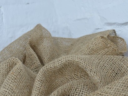 Close-up of wrinkled sackcloth with fine, natural fibers on a white surface, highlighting the texture of sustainable, plant-based fabrics used in eco-friendly fashion