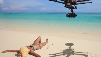 Un dron sobrevolando a una chica que toma el sol en la playa