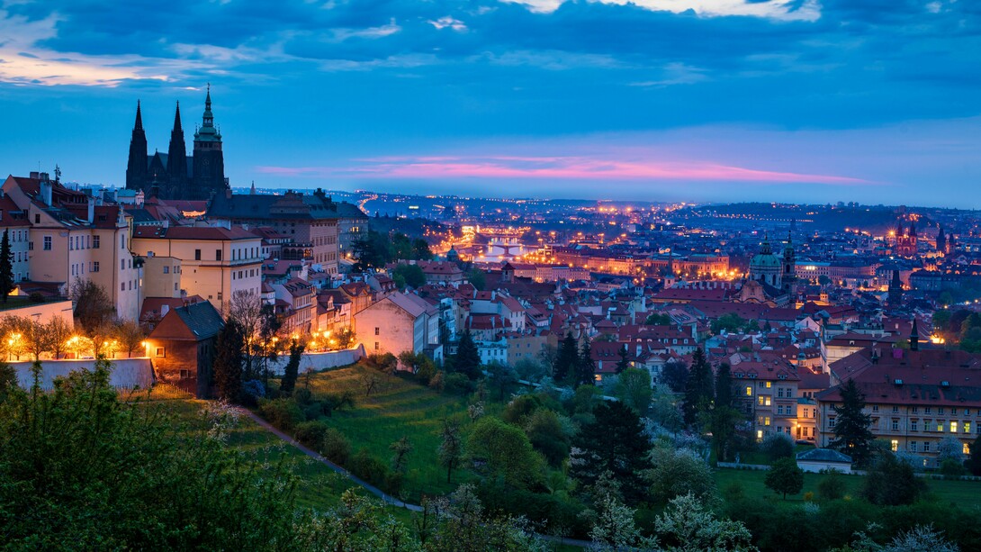 Prague’s historic rooftops and landmarks illuminated against the twilight sky, representing the city’s magical character