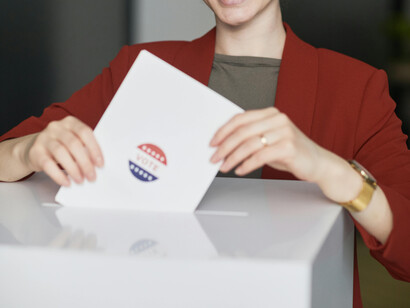 A woman in a red coat casting her vote